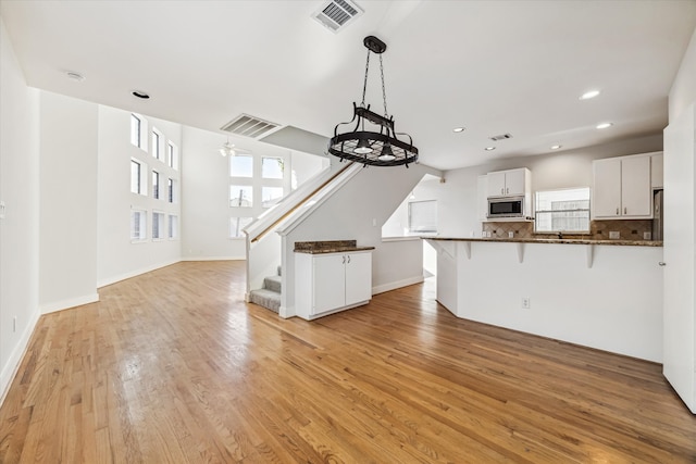 kitchen with ceiling fan, white cabinets, tasteful backsplash, stainless steel microwave, and light hardwood / wood-style floors