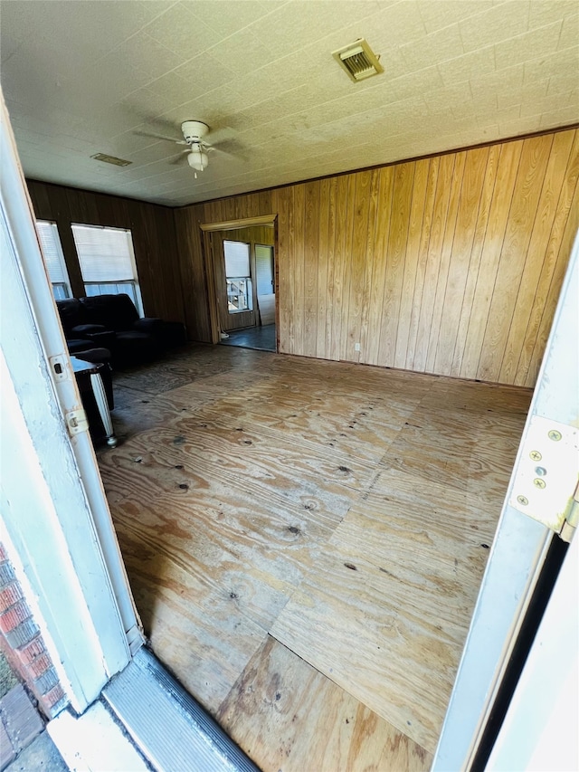 interior space featuring ceiling fan and wood walls