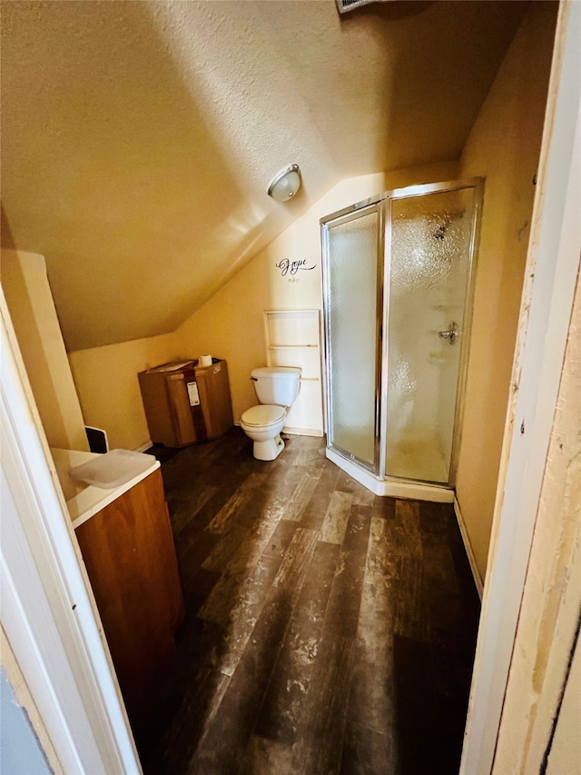 bathroom with lofted ceiling, walk in shower, wood-type flooring, toilet, and vanity