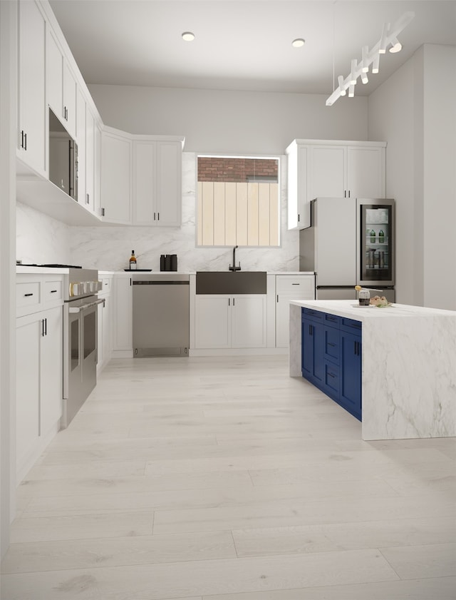 kitchen featuring appliances with stainless steel finishes, white cabinets, backsplash, blue cabinetry, and sink