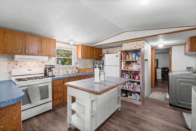 kitchen featuring dark hardwood / wood-style flooring, vaulted ceiling, washer / dryer, and white appliances