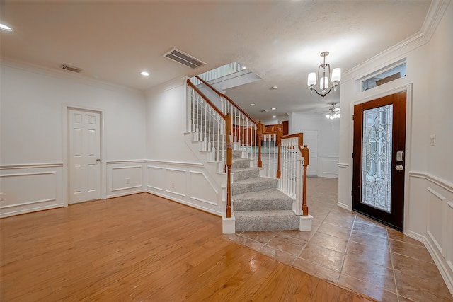 foyer featuring ceiling fan with notable chandelier, ornamental molding, and light hardwood / wood-style flooring