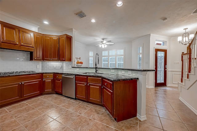 kitchen with ornamental molding, kitchen peninsula, stainless steel appliances, dark stone countertops, and ceiling fan with notable chandelier