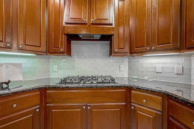 kitchen with decorative backsplash, dark stone countertops, and stainless steel gas cooktop