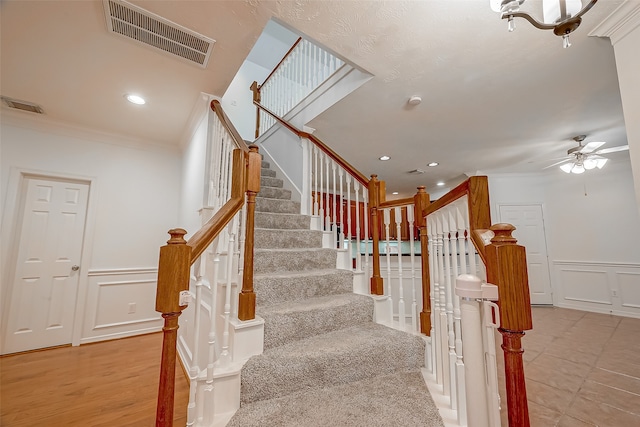 stairway featuring ceiling fan, ornamental molding, a skylight, and hardwood / wood-style floors