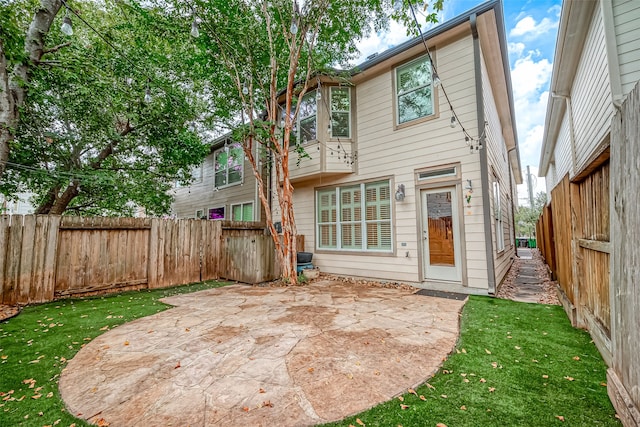 back of house featuring a patio and a yard