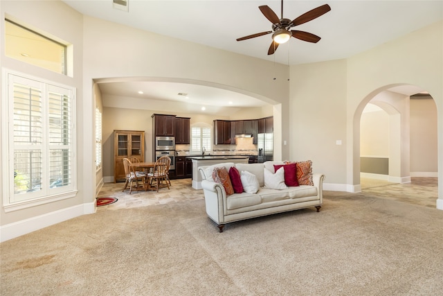 carpeted living room featuring sink, ceiling fan, and a wealth of natural light