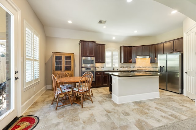 kitchen featuring appliances with stainless steel finishes, tasteful backsplash, a kitchen island, and a wealth of natural light