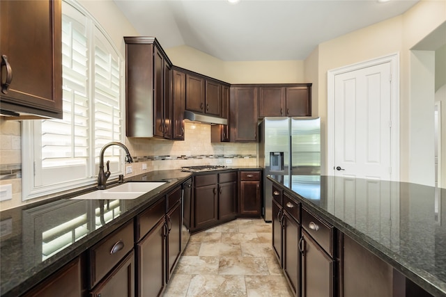 kitchen featuring tasteful backsplash, stainless steel appliances, dark brown cabinets, dark stone counters, and sink