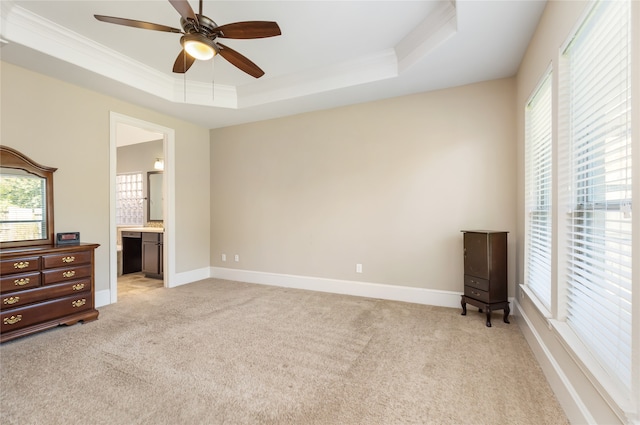 carpeted bedroom featuring crown molding, a tray ceiling, ceiling fan, and ensuite bathroom