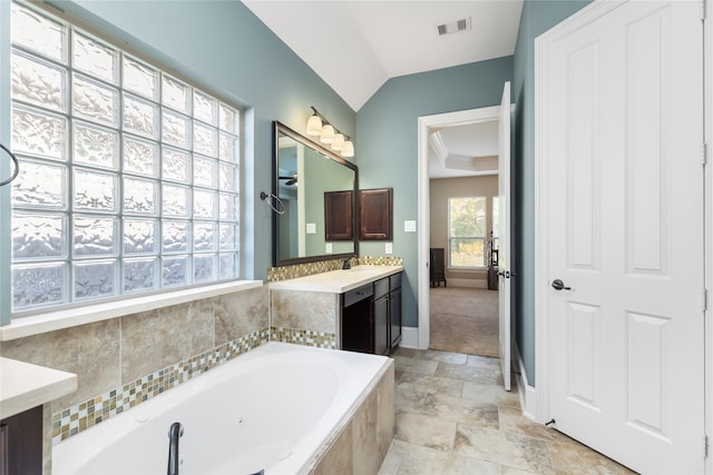 bathroom with vaulted ceiling, tiled bath, and vanity