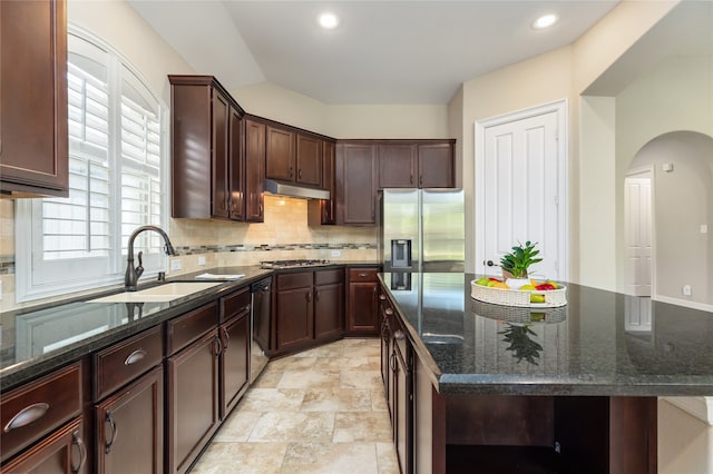 kitchen featuring tasteful backsplash, sink, a kitchen island, stainless steel appliances, and dark stone countertops