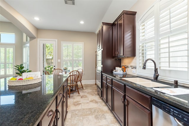 kitchen featuring dark stone counters, backsplash, dishwasher, and sink