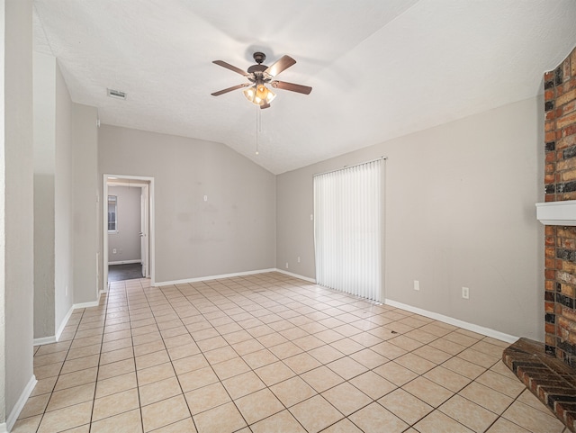 unfurnished living room with a textured ceiling, lofted ceiling, a brick fireplace, light tile patterned floors, and ceiling fan