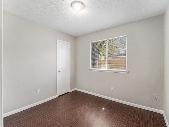 unfurnished room with a textured ceiling and dark hardwood / wood-style floors