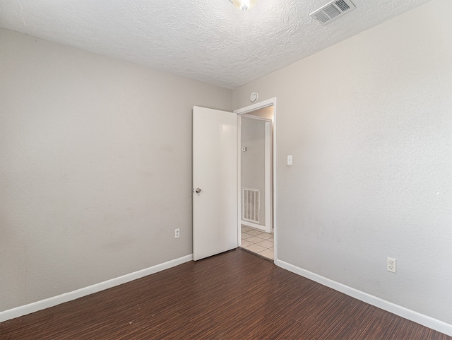 unfurnished room with a textured ceiling and dark hardwood / wood-style floors