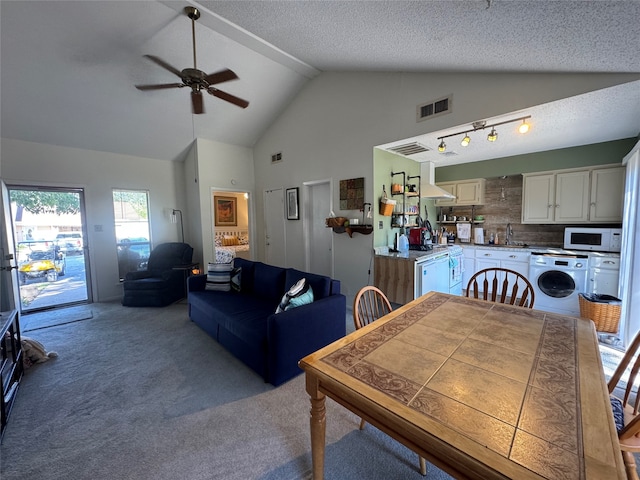 dining room featuring washer / clothes dryer, sink, light carpet, high vaulted ceiling, and ceiling fan