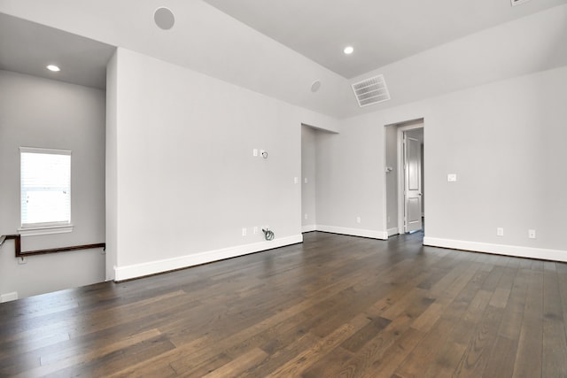 empty room featuring vaulted ceiling and dark hardwood / wood-style flooring