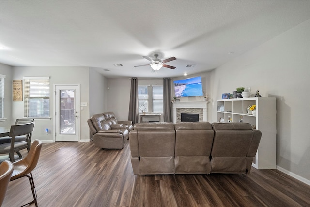 living room with a fireplace, dark wood-type flooring, and ceiling fan