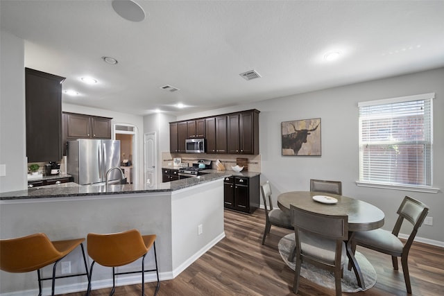 kitchen featuring dark brown cabinetry, appliances with stainless steel finishes, and dark wood-type flooring