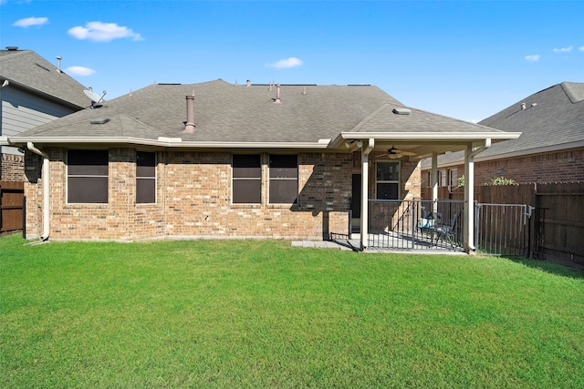 rear view of property with ceiling fan, a patio area, and a yard