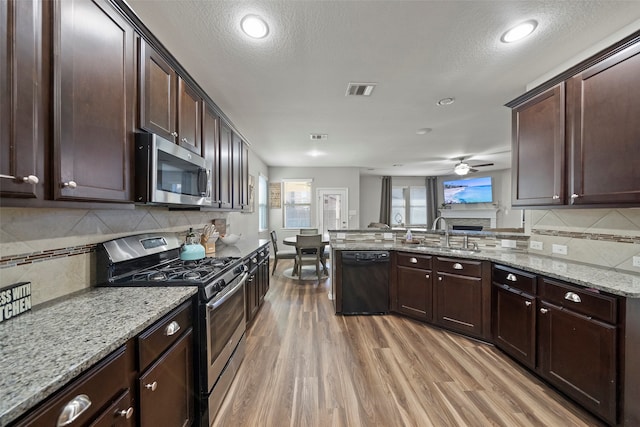 kitchen featuring appliances with stainless steel finishes, light hardwood / wood-style floors, a textured ceiling, ceiling fan, and sink