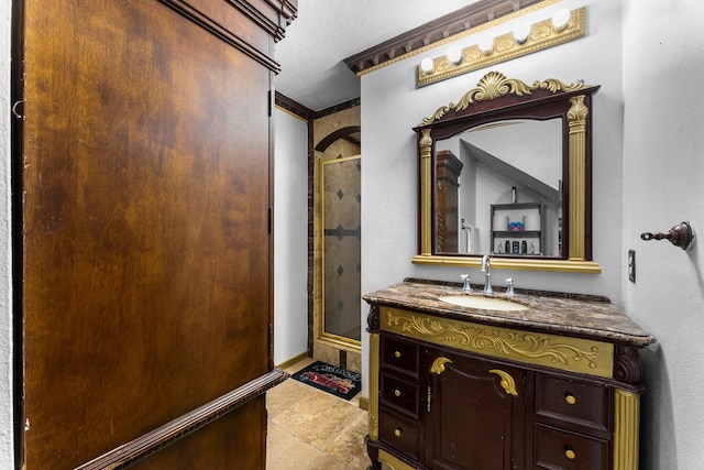 full bath with baseboards, vanity, a textured ceiling, and a stall shower