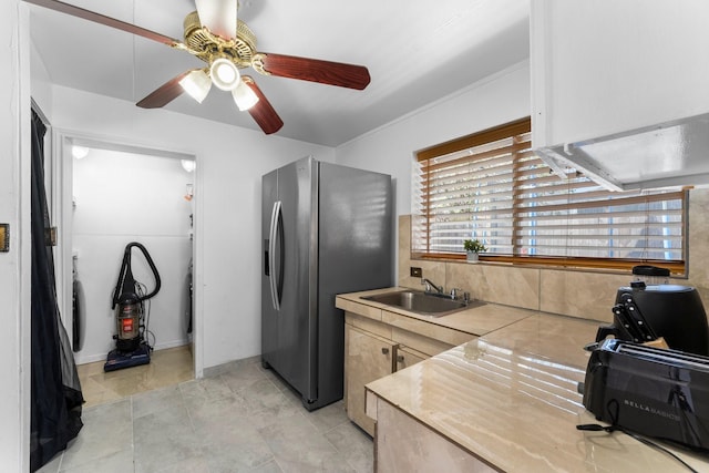 kitchen with ceiling fan, a sink, light countertops, and stainless steel fridge
