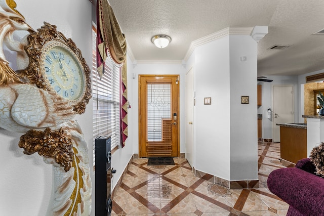 foyer entrance with a textured ceiling and ornamental molding