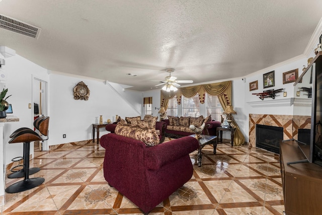 living area featuring visible vents, a ceiling fan, light tile patterned flooring, a fireplace, and a textured ceiling
