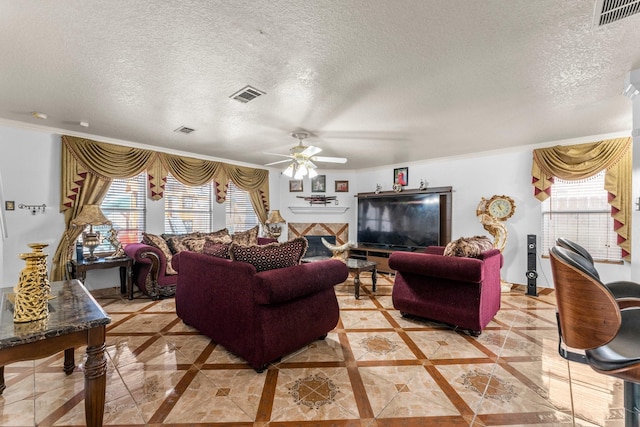 living room featuring a ceiling fan, visible vents, a textured ceiling, and ornamental molding