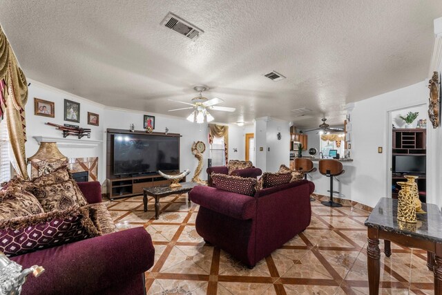living room with a textured ceiling, visible vents, and a ceiling fan