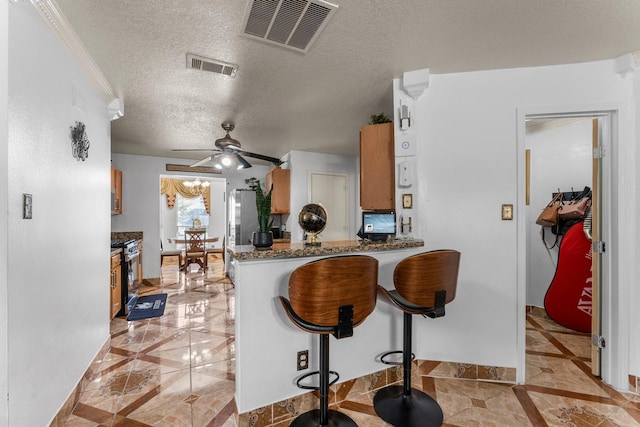 kitchen with a peninsula, a textured ceiling, visible vents, and a ceiling fan