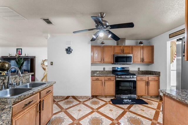 kitchen with a sink, a textured ceiling, visible vents, ceiling fan, and appliances with stainless steel finishes