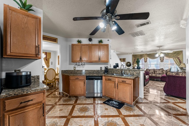 kitchen featuring stainless steel dishwasher, a ceiling fan, a sink, a textured ceiling, and visible vents