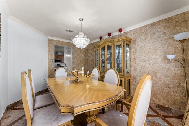 dining room featuring baseboards, visible vents, a chandelier, and crown molding