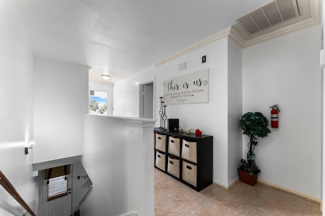 hallway featuring visible vents, a textured ceiling, and light tile patterned floors