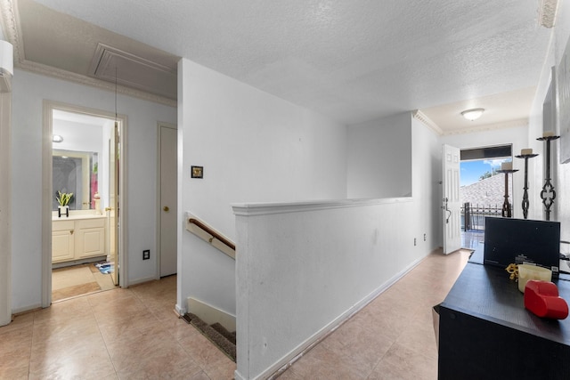 hall with ornamental molding, an upstairs landing, baseboards, attic access, and a textured ceiling
