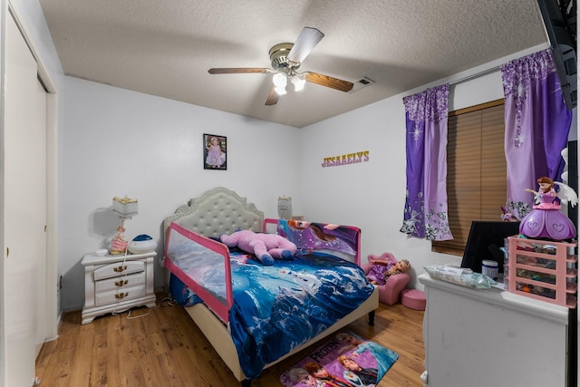bedroom featuring a textured ceiling, wood finished floors, visible vents, and ceiling fan
