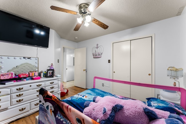 bedroom with a textured ceiling, ceiling fan, light hardwood / wood-style flooring, and a closet