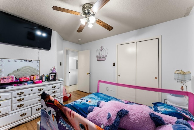 bedroom with light wood finished floors, a ceiling fan, a textured ceiling, and a closet