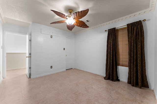 spare room with a ceiling fan, a textured ceiling, light tile patterned flooring, baseboards, and visible vents