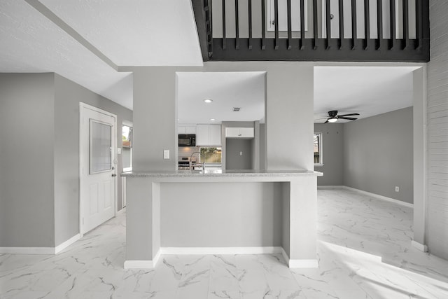 kitchen with decorative backsplash, white cabinets, kitchen peninsula, ceiling fan, and sink