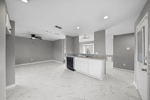 kitchen featuring ceiling fan, dishwasher, sink, and white cabinetry