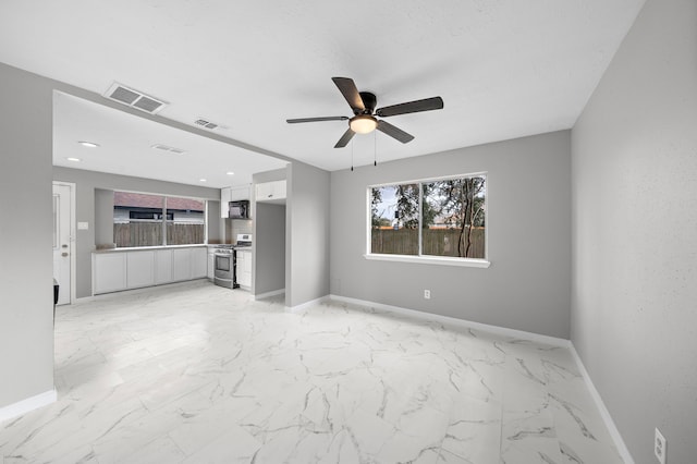 unfurnished living room featuring ceiling fan and a wealth of natural light