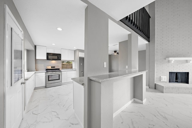 kitchen with kitchen peninsula, gas range, ceiling fan, and white cabinetry