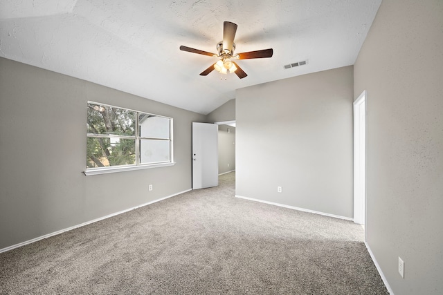 unfurnished room with lofted ceiling, ceiling fan, carpet floors, and a textured ceiling