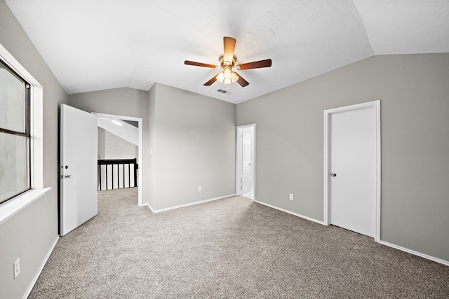 carpeted spare room featuring ceiling fan and lofted ceiling