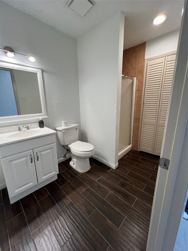 bathroom featuring a textured ceiling, an enclosed shower, vanity, and toilet