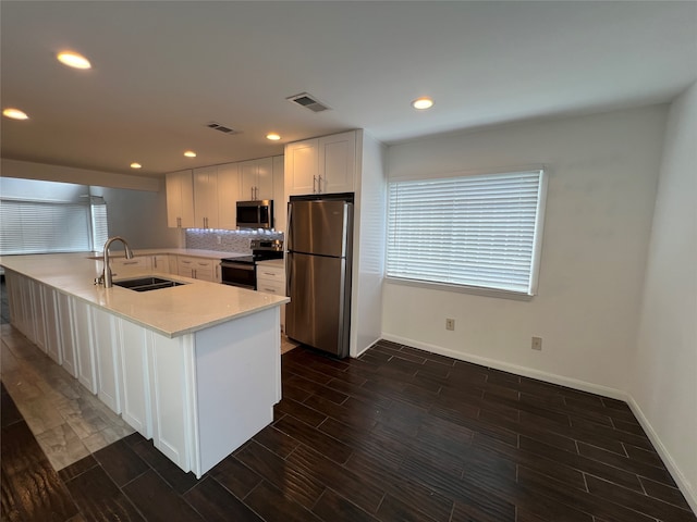 kitchen with appliances with stainless steel finishes, white cabinetry, backsplash, light stone countertops, and sink